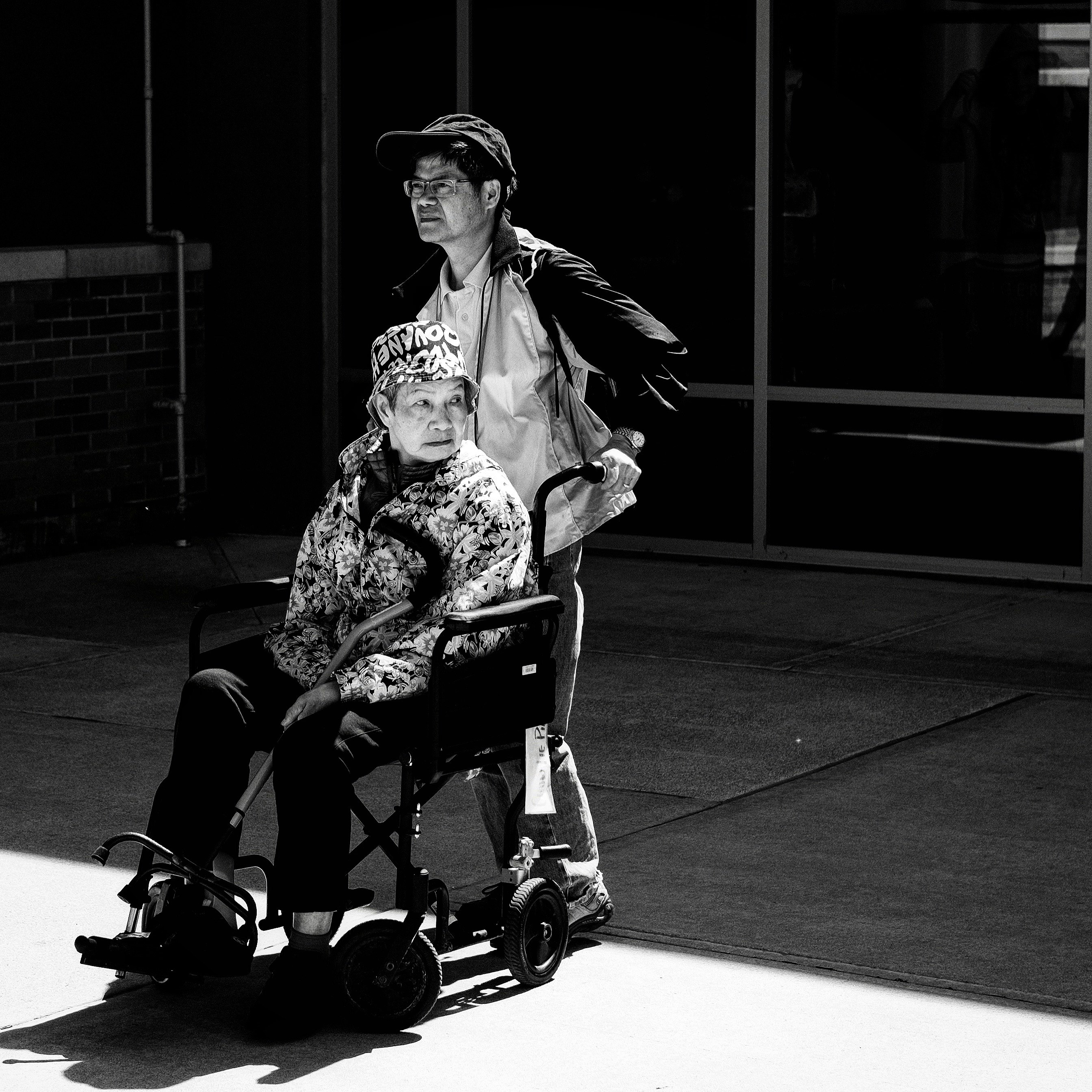 gray scale photo of man pushing wheelchair